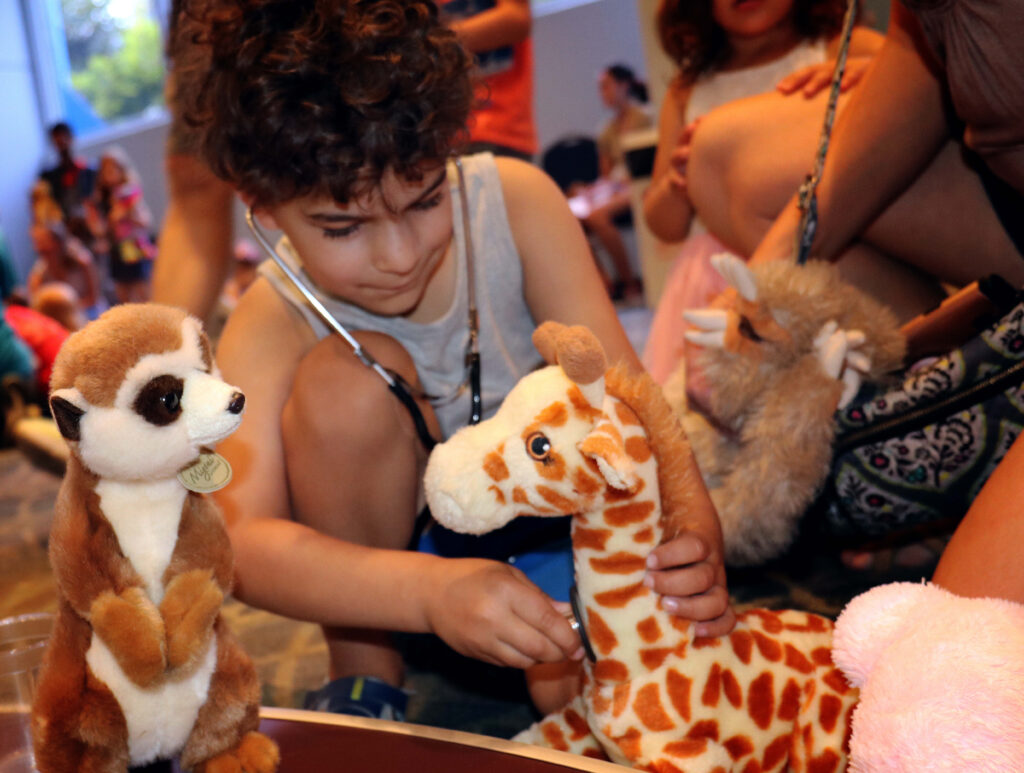 Child checking giraffe plush with stethoscope